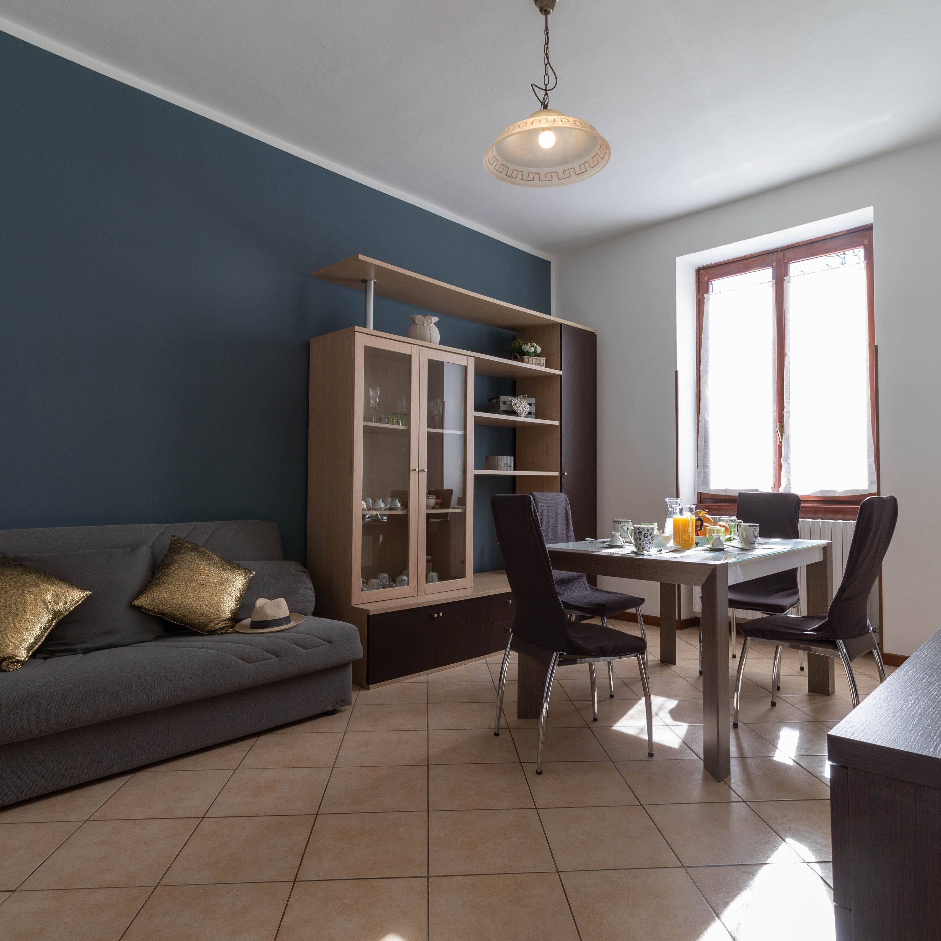 Un salon moderne comprenant un canapé, une table à manger, des chaises et un meuble avec des portes en verre.