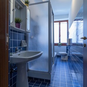 A bathroom with a sink, toilet, and shower area.