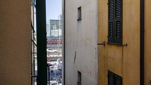 A narrow alleyway between buildings with a visible street view, including parked cars and a building with a sign. - Comfy Apartment Near the Harbor by Wonderful Italy (Genoa)