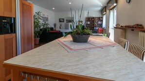 A kitchen with a marble countertop, a potted plant, and a dining area with striped chairs. - La Soliva Big House in Bellano (Bellano)