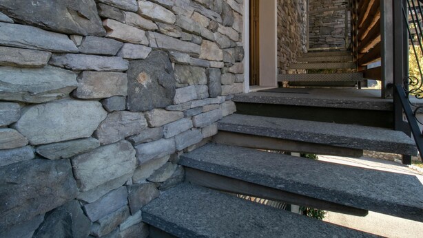 A stone staircase leading to a wooden door, with a metal railing on the right. - La Soliva Big House in Bellano (Bellano)