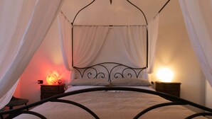 A bed with a canopy, two bedside tables with lamps, and a chair. - La Soliva Big House in Bellano (Bellano)
