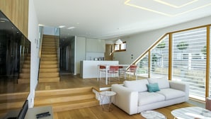 A modern living room with a white sofa, a coffee table, and a staircase leading to a kitchen area. - Villa Calla Zadarvillas (Zadar)