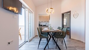 A modern dining area with a wooden table, green upholstered chairs, and pendant lighting. - Beautiful apartment in Prizna with WiFi (Prizna)