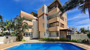 A modern apartment building with a swimming pool, balconies, and palm trees. - Le Mirage Cozy Beach Apartment, 5 min walk to the beach. Enjoy sunset view (Flic en Flac)
