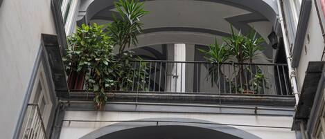 Un immeuble à plusieurs étages doté de balcons, de fenêtres en arc de cercle et de plantes en pot.