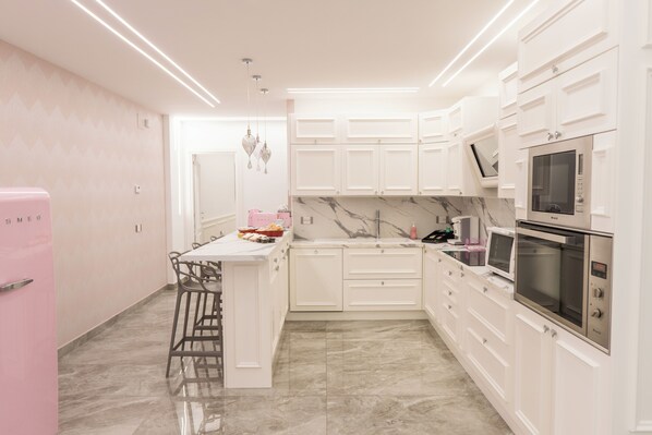 A modern kitchen with white cabinetry, a marble backsplash, and stainless steel appliances. - Suite d'élite Chiaia (Naples)