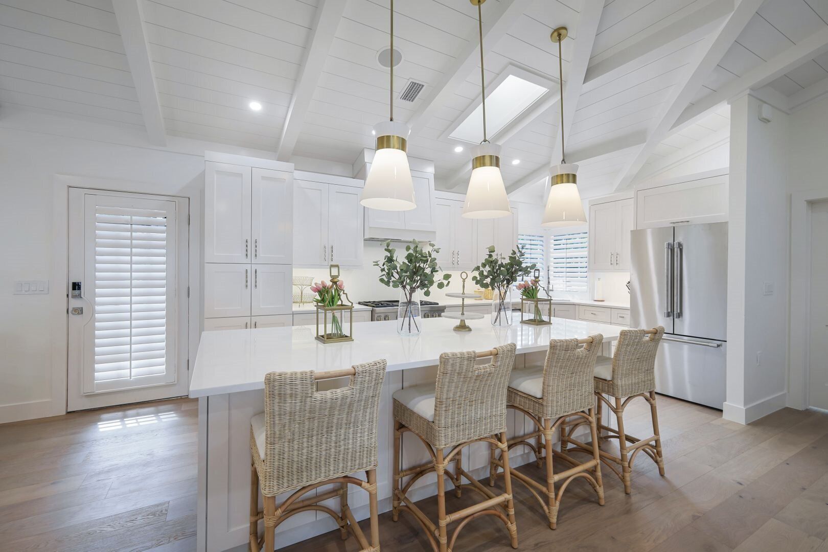 A spacious kitchen with a large island, white cabinetry, and a modern stainless steel refrigerator.