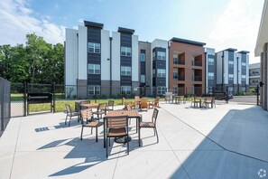 A modern apartment complex with outdoor seating areas and a fenced courtyard. - Landing | Amazing 2BD, Clubhouse, Pool (Indianapolis)