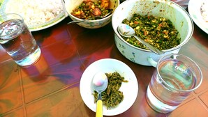 A table with various dishes including rice, a vegetable curry, and a green leafy dish, along with two glasses of water. - Heaven Homestay (Darjeeling)