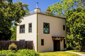 A two-story building with a chimney, a fenced yard, and a pathway leading to the entrance. - Private Modern Home w/ Rooftop Deck, EV Charger (Burlington)