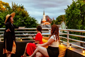 Three people sitting on a balcony with a railing, overlooking a building with a spire. - Private Modern Home w/ Rooftop Deck, EV Charger (Burlington)
