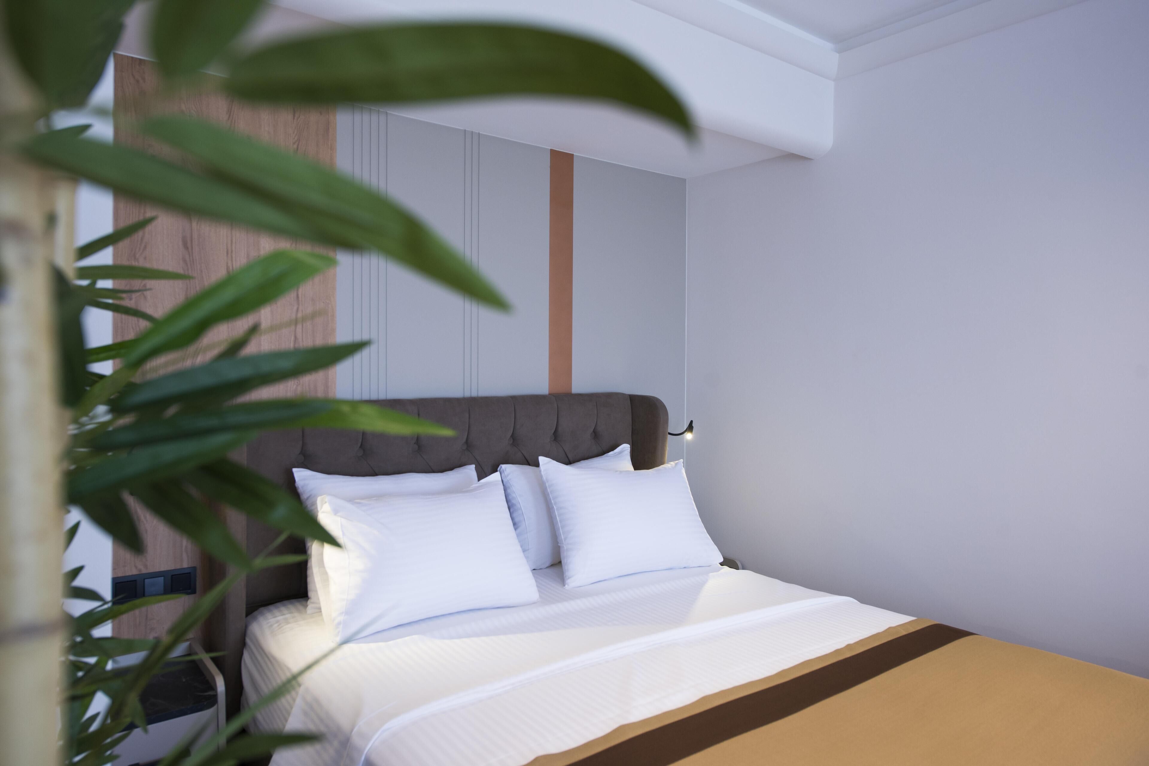 A neatly made bed with white linens and a brown accent, a tufted headboard, and a vertical wooden panel on the wall.