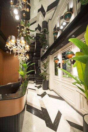 Eine Hotelhalle mit Marmorboden, einer Rezeption und einer Treppe.