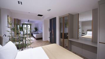 Una habitación de hotel moderna con cama, mesita de noche y un espejo grande. Hay una planta en maceta y vistas del área de estar.