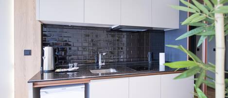 A modern kitchen with a black countertop, stainless steel appliances, and a dishwasher.