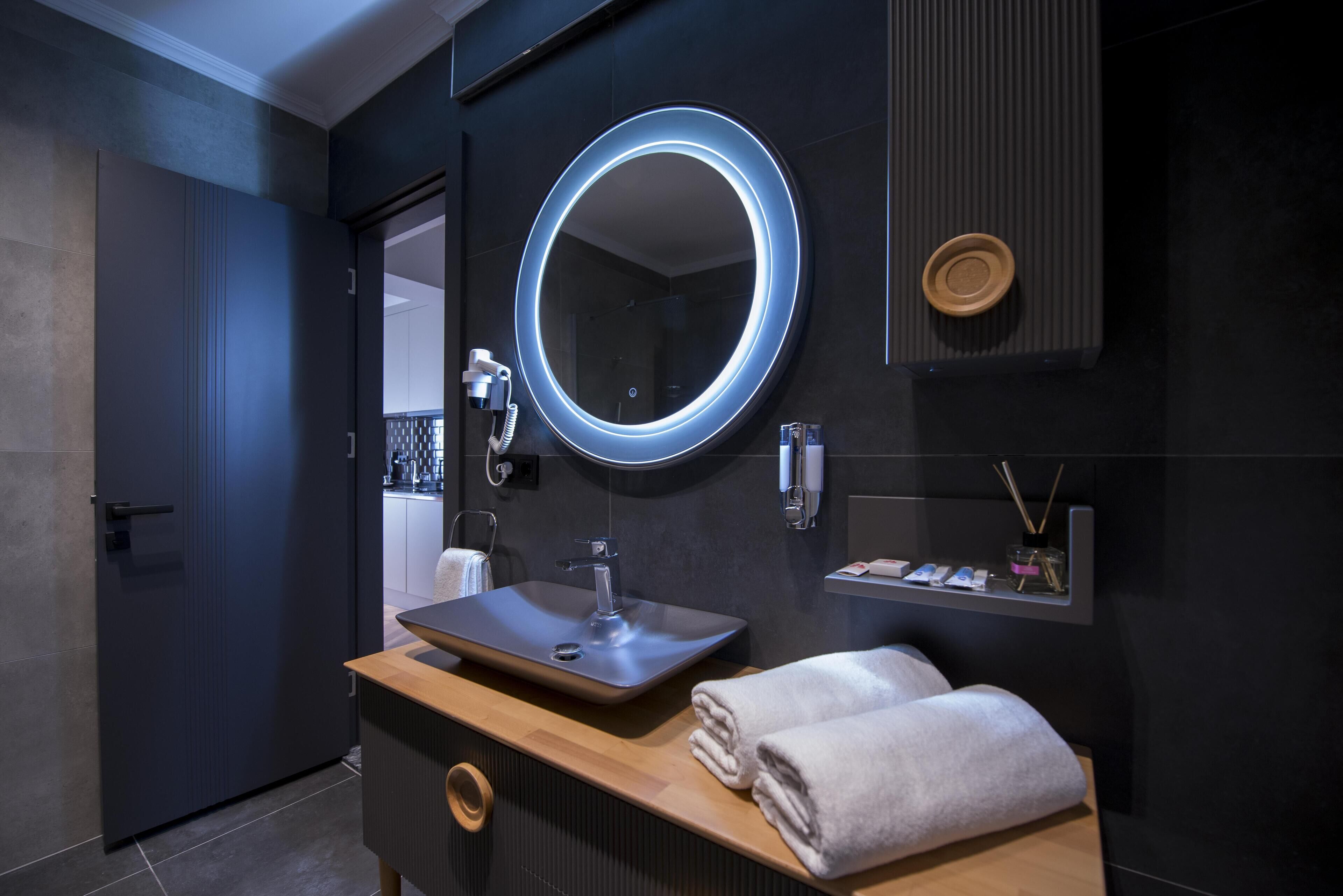Une salle de bain moderne avec un miroir rond, un lavabo et un meuble-lavabo en bois.