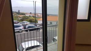 Balkon med udsigt over parkerede biler og et kystlandskab.