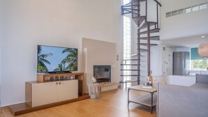 Een moderne woonkamer met een televisie, open haard en een wenteltrap.