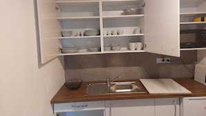 A kitchen with white cabinets, a wooden countertop, a sink, and a microwave. - Gite de Moulin Maurt 1 (Xertigny)