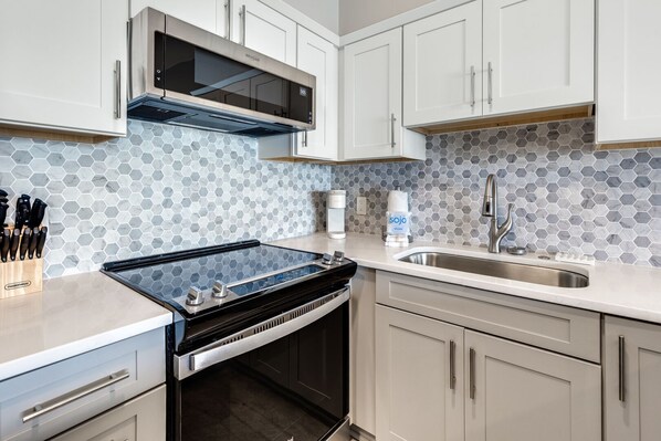 A modern kitchen with a built-in stove, a microwave, and a stainless steel sink.