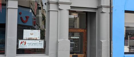 A building facade with a sign for 'Woodfired Studios & Bike Store' and a window displaying 'Scorchini's Pizzeria'.