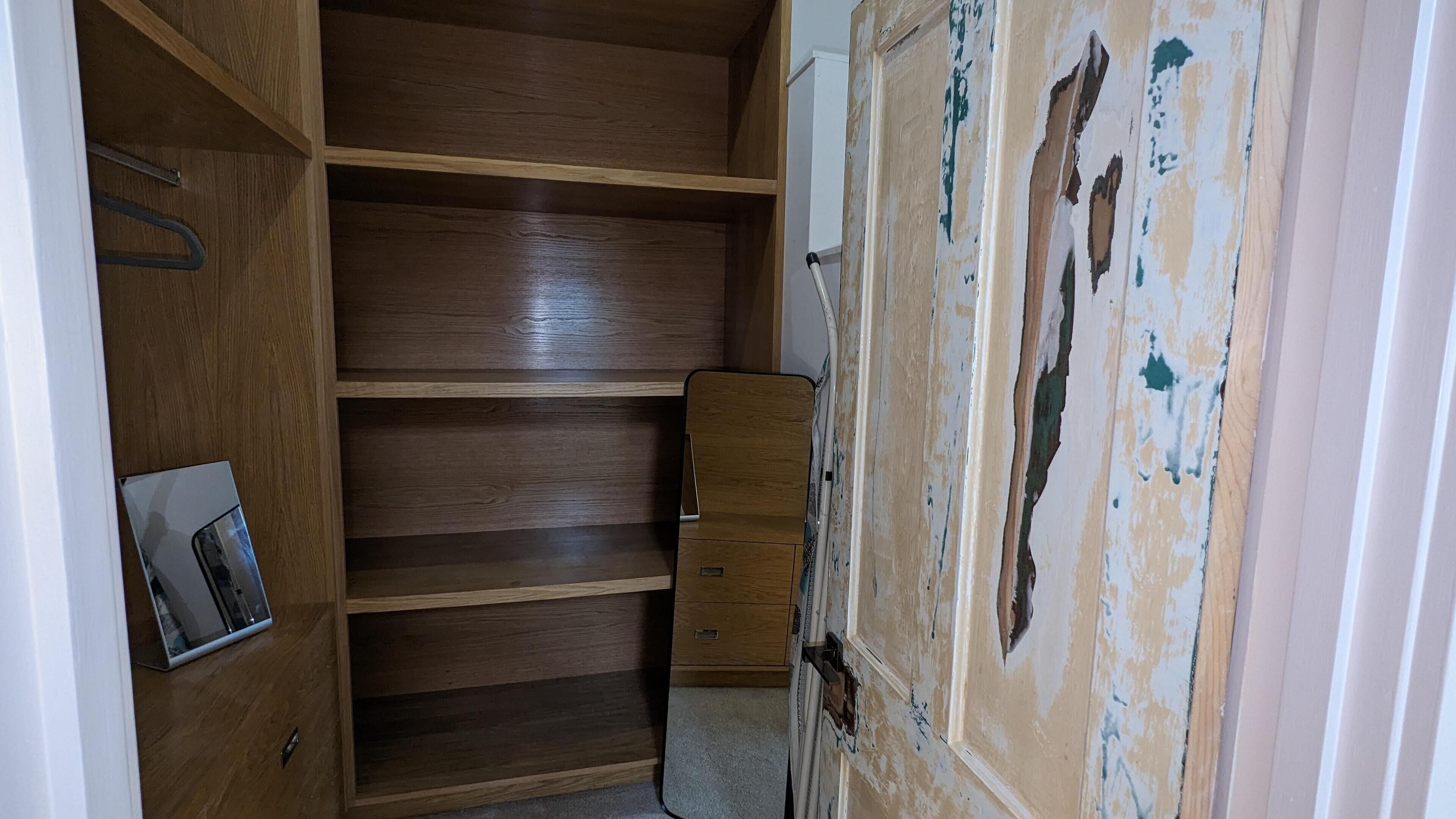 A walk-in closet with wooden shelving and a small dresser.