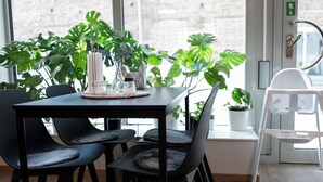 A modern dining area with a black table and chairs, a vase with flowers, and potted plants. - Ahlgrens Hotell Bed & Breakfast (Gävle)