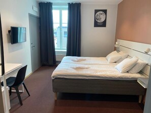 A hotel room with a bed, a desk, a chair, a television, and a window with curtains. - Ahlgrens Hotell Bed & Breakfast (Gävle)