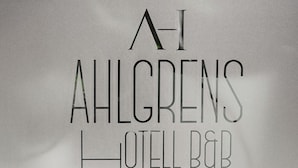 Een bordje voor AHLGRENS HOTELL B&B, met een achtergrond van groen bladerwerk.