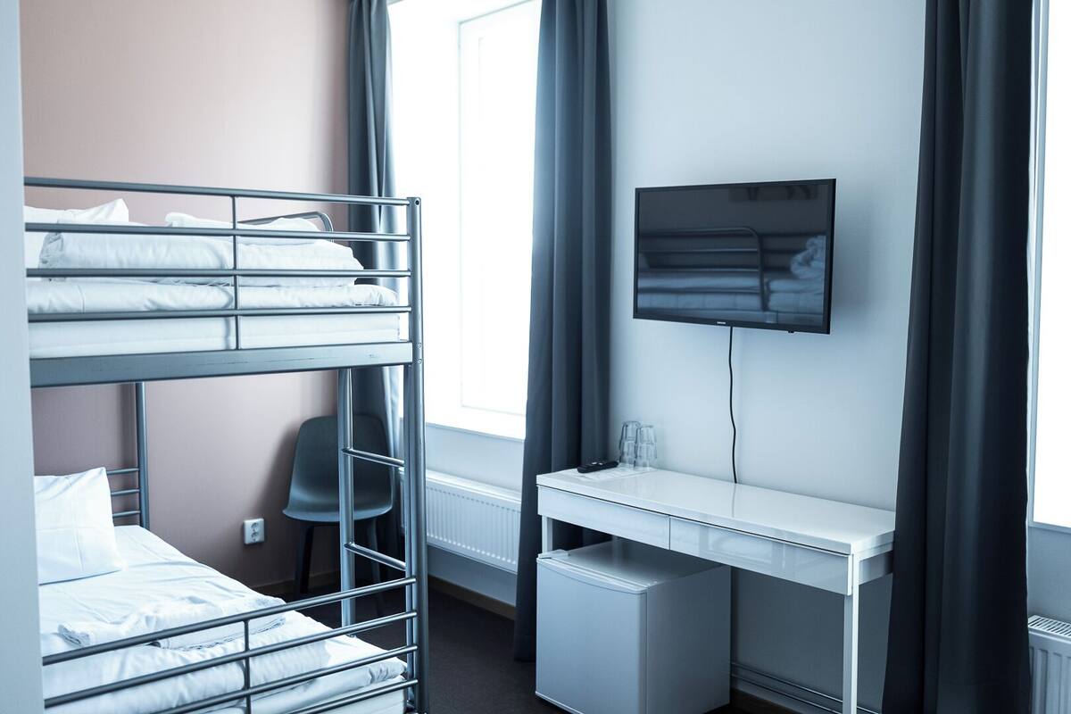 A bunk bed with a desk and a TV mounted on the wall.