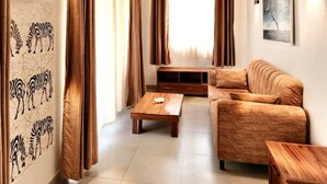 A living room with a wooden ceiling, a sofa, a coffee table, and curtains. - The Dream Village (Kiwengwa)