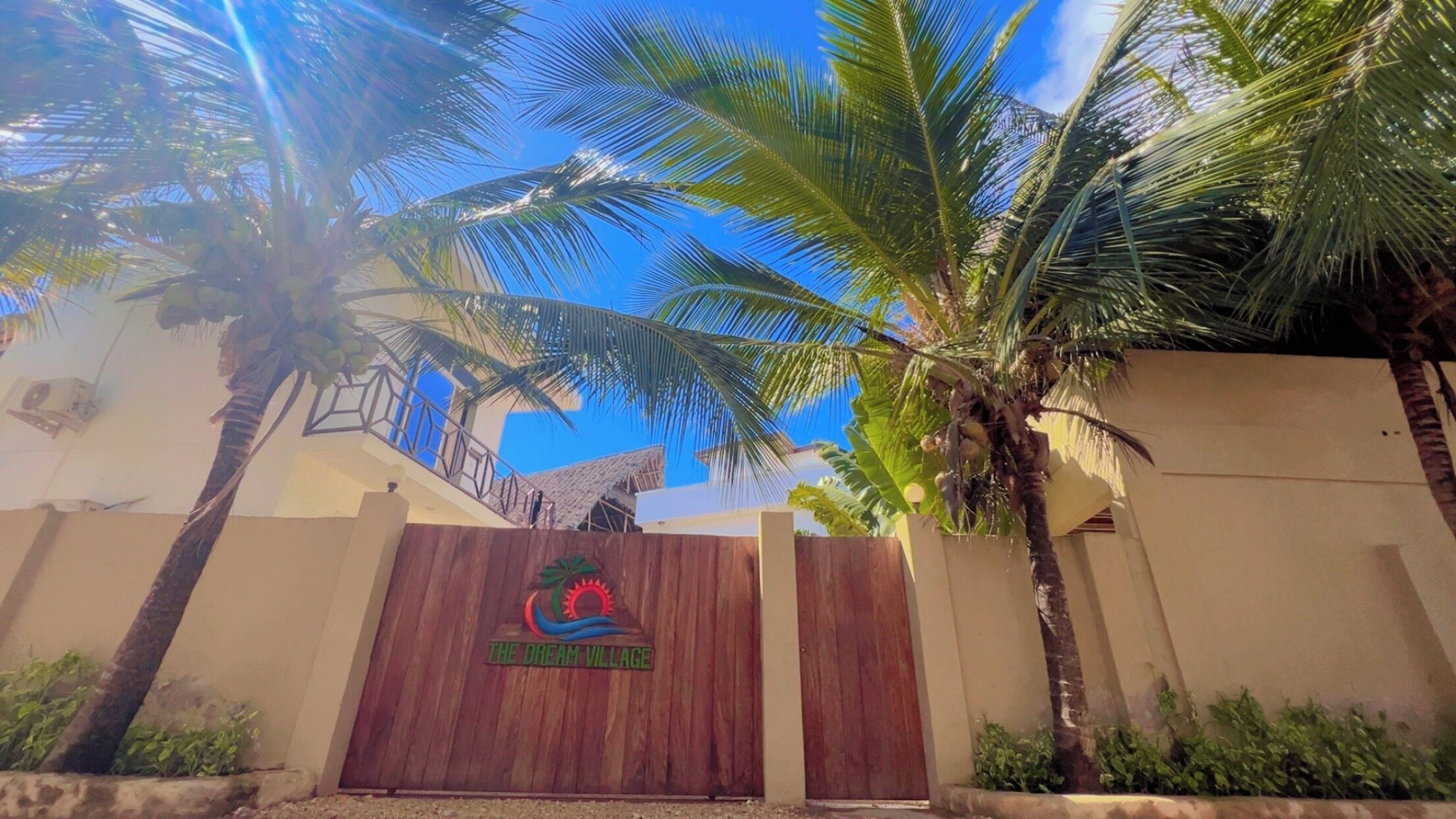 A gated entrance with a wooden door and a logo that reads 'The Dream Village.'