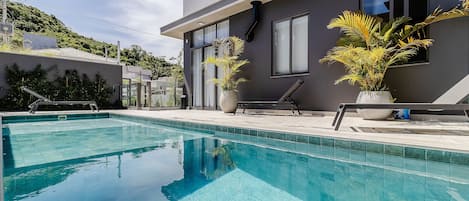 Un edificio moderno con piscina, ventanas amplias y plantas en macetas.