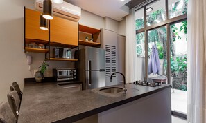Una cocina moderna con electrodomésticos integrados, un ventanal con vistas a zonas verdes y una zona de comedor con sillas.