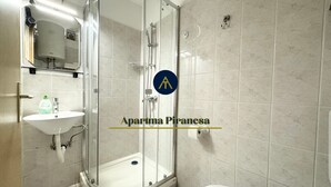 Un baño moderno con ducha envuelta en vidrio, un lavamanos y un inodoro.