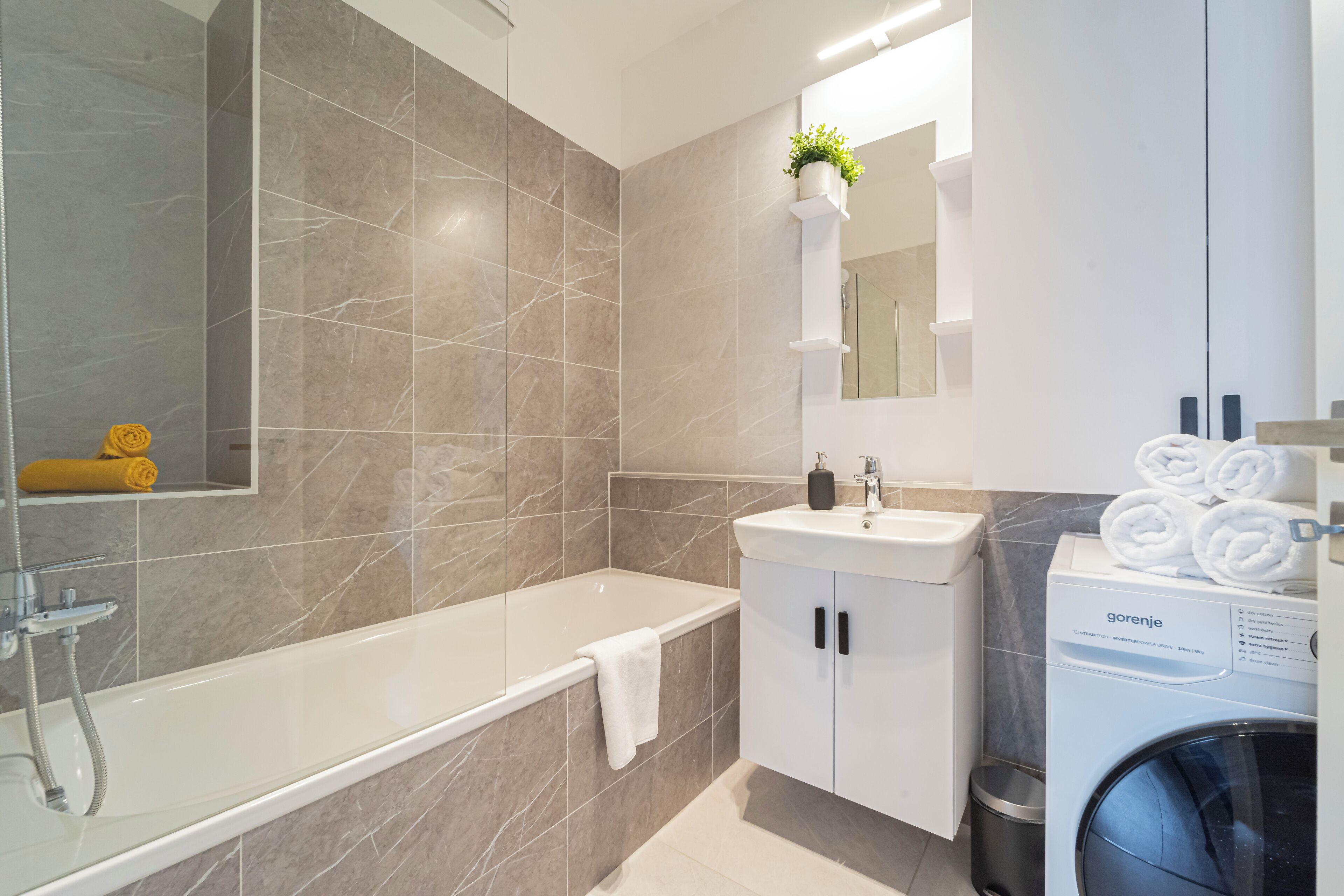 Un baño moderno con bañera, lavamanos y lavadora.