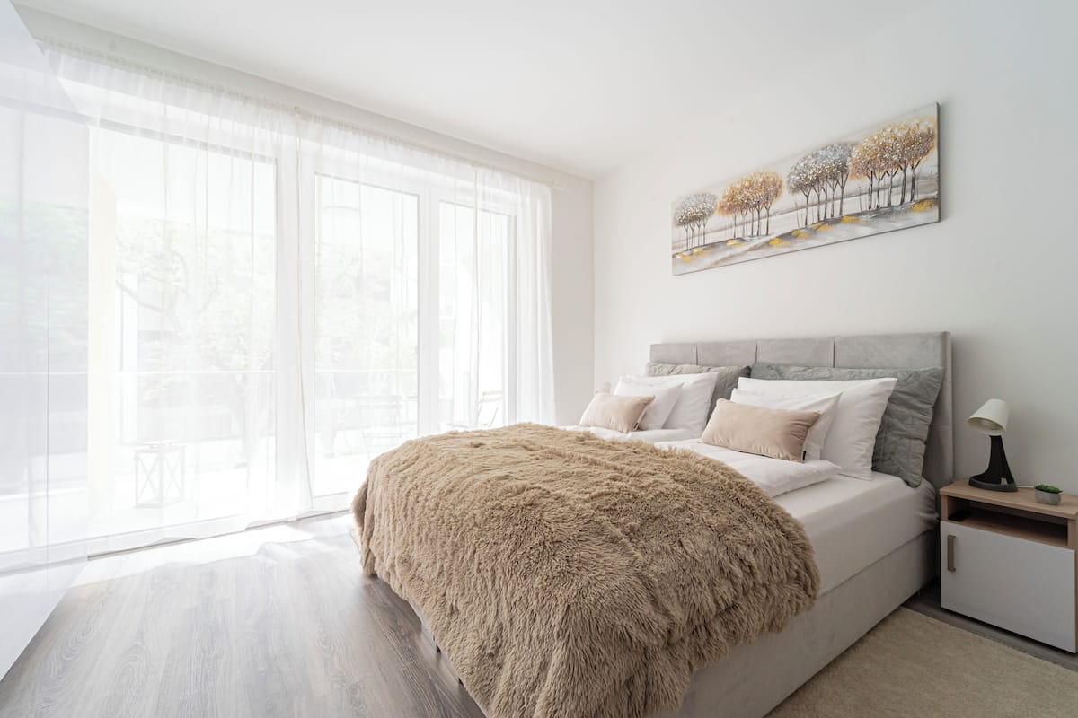 A modern bedroom with a large bed, a nightstand, and a painting on the wall.