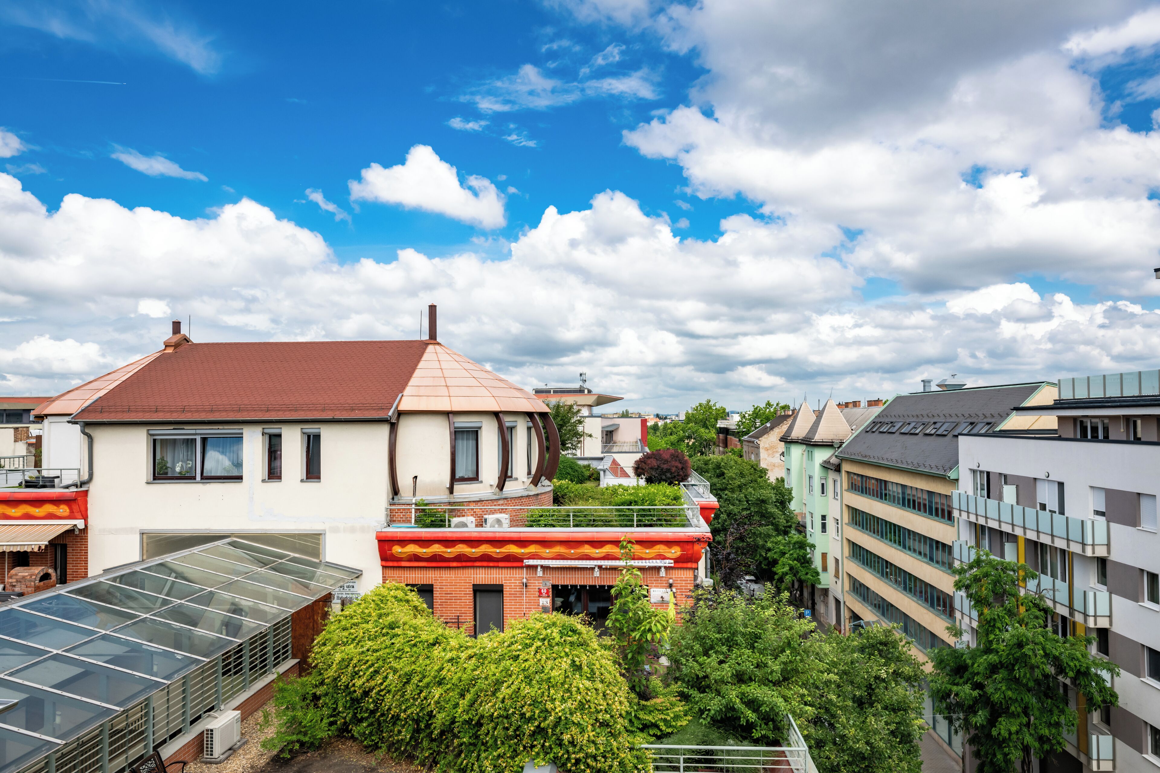 A residential building with a red roof, a glass conservatory, and a balcony.