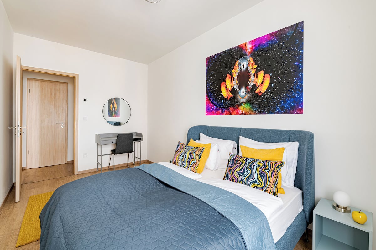 A bedroom with a bed, a desk, and a chair.