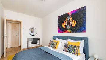 A bedroom with a bed, a desk, and a chair.