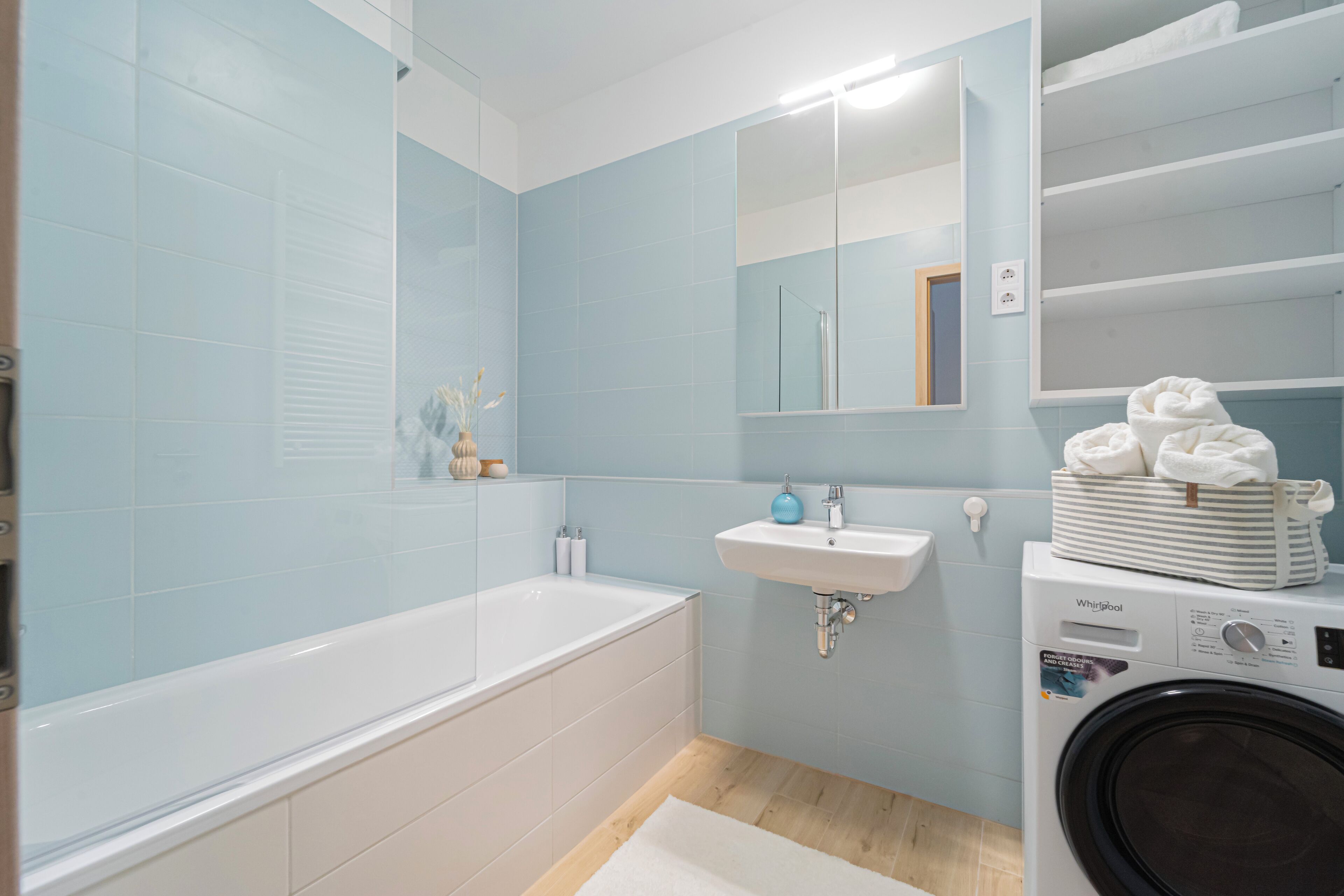 Un baño moderno con bañera, lavamanos y una lavadora Whirlpool.