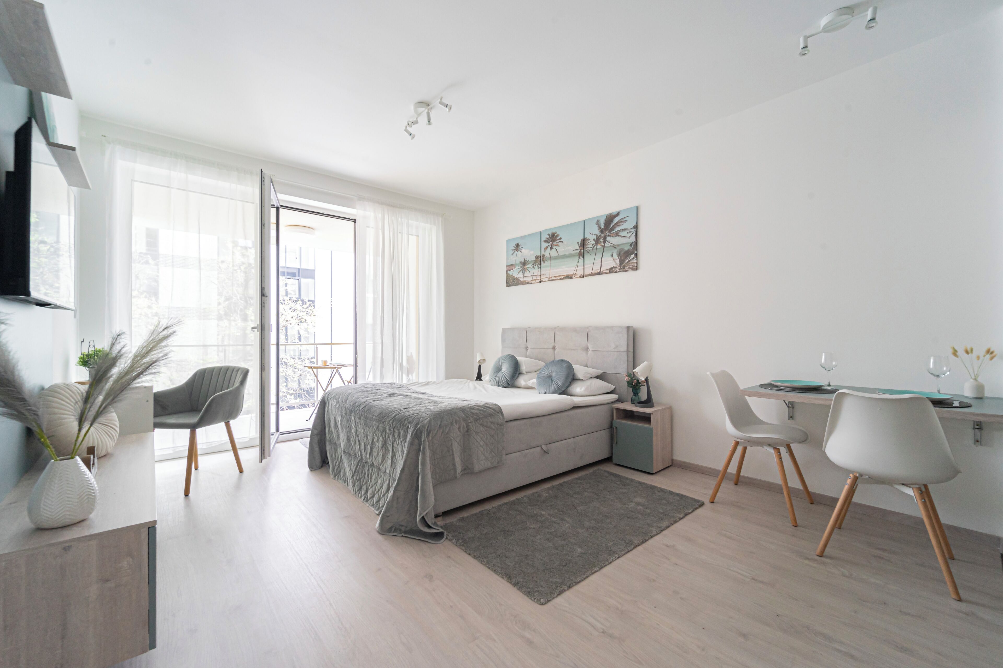 A modern bedroom with a bed, bedside tables, a desk, and chairs.