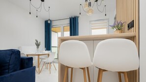 Cozinha moderna com cadeiras brancas, um sofá azul e um espaço de refeições com mesa e cadeiras brancas.