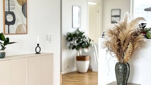 A modern interior with a minimalist design, featuring a wooden cabinet, a vase with dried plants, and a framed abstract artwork on the wall. - Modern Apartment with a View

 (København)