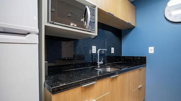 A kitchen with a microwave, sink, and wooden cabinets.