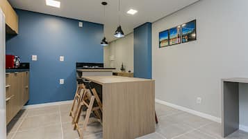 A modern kitchen with blue walls, a wooden island, and pendant lighting.