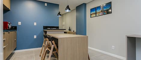 A modern kitchen with blue walls, a wooden island, and pendant lighting.