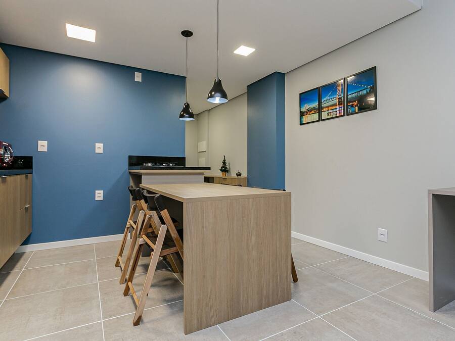 A modern kitchen with blue walls, a wooden island, and pendant lighting.