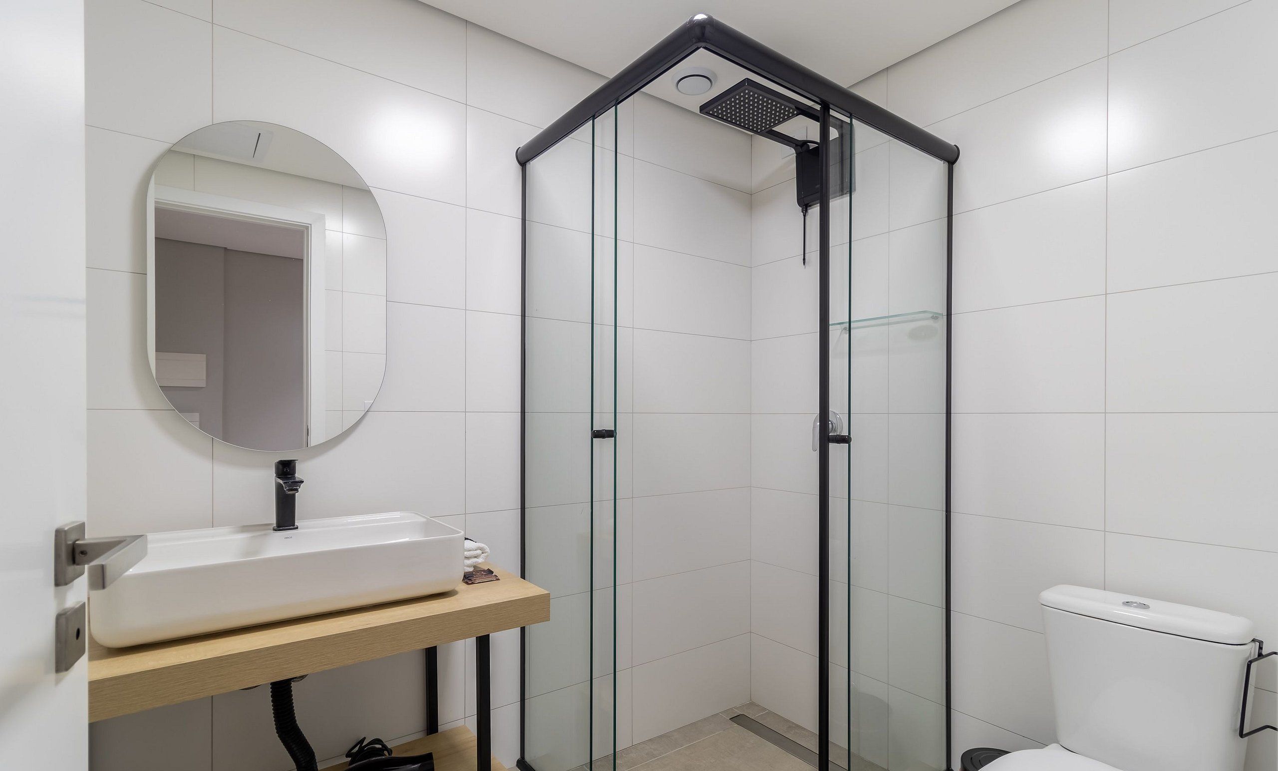 A modern bathroom with a glass-enclosed shower, a white sink with a mirror, and a toilet.